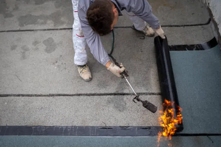 Worker applies heat to a waterproof membrane for roof. 