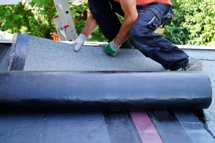 A worker installs a waterproof membrane for roof protection.