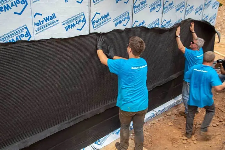 Workers install a moisture barrier for garage floor waterproofing in a new home.