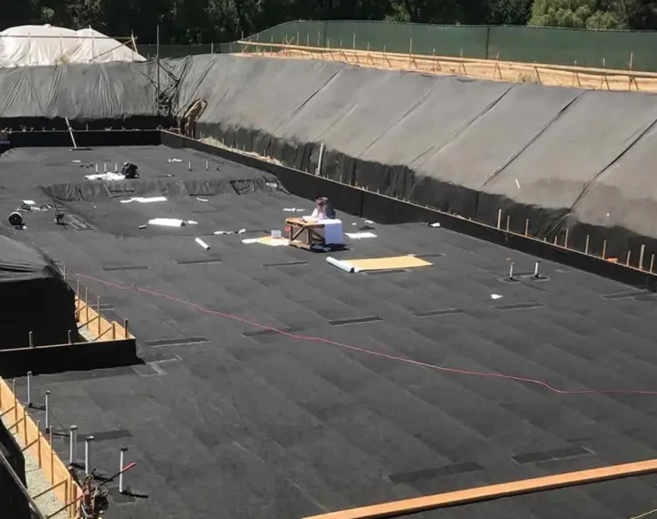 Workers install a vapor barrier in a building's crawl space.