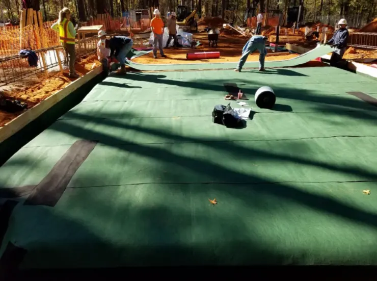 A vapor barrier is applied to the foundation as a first step in the building process.